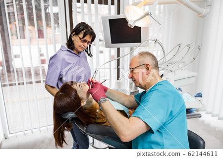Senior male dentist doctor and his female nurse treats a patient. Dentistry and healthcare, oral care concept 62144611