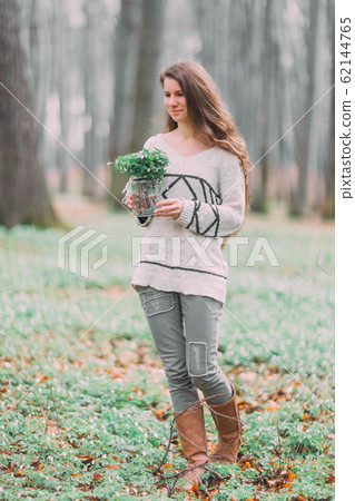 beautiful young girl woman walking through the green forest in spring, holding glass ar with white spring flowers beautiful young girl woman walking through the green forest in spring, holding glass ar with white spring flowers 62144765