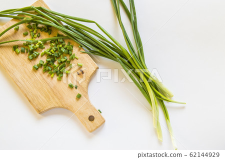 Fresh green onion feathers and cut into pieces on a wooden chopping Board. Top view, flat lay, copying space isolated on white background Fresh green onion feathers and cut into pieces on a wooden chopping Board. Top view, flat lay, copying space isolated on white background 62144929