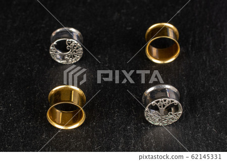 Stylish ear plug on grey stone 62145331