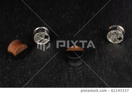 Stylish ear plug on grey stone Stylish ear plug on grey stone 62145337
