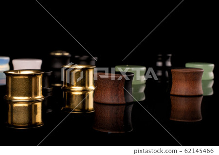 Stylish ear plug isolated on black glass Stylish ear plug isolated on black glass 62145466