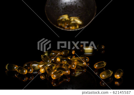 Golden fish oil isolated on black glass 62145587