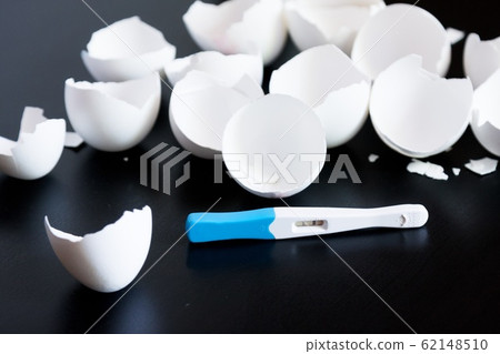 Infertility. Negative pregnancy test and eggshell on black background 62148510