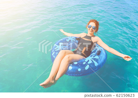 Beautiful young woman relax on inflatable ring in sea water Beautiful young woman relax on inflatable ring in sea water 62150623