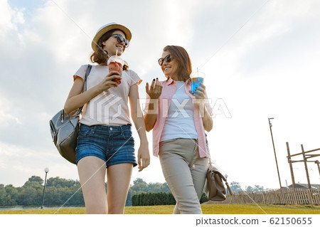 Mother daughter walking on the lawn in the park, The relationship between parent and child teenager, sunny summer day 62150655