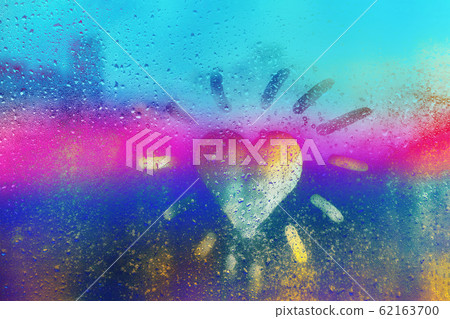 Hand drawn orange shape heart like sun for text on muddy glass wet blue, yellow and purple neon window in city Hand drawn orange shape heart like sun for text on muddy glass wet blue, yellow and purple neon window in city 62163700