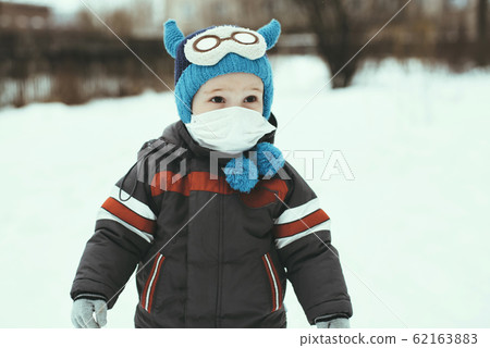 portrait of a child boy in a medical mask on the street 62163883
