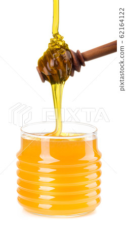 Glass jar full of honey and wooden dipper isolated on white background 62164122