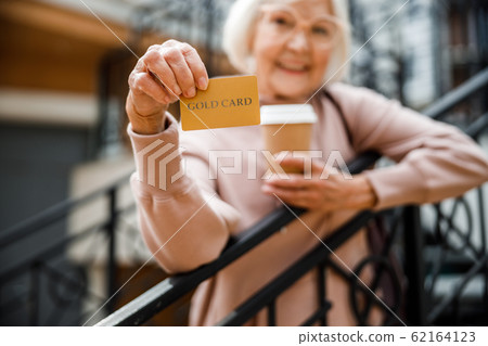 Happy elderly female with credit card outdoors stock photo 62164123