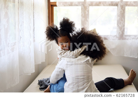 The two African girl siblings are having fun and tease each other in the bedroom during the holidays. 62165728