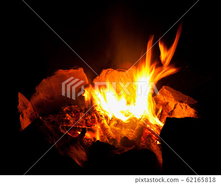 Flame fire on a black night background. Bonfire fenced in rough large stones. 62165818