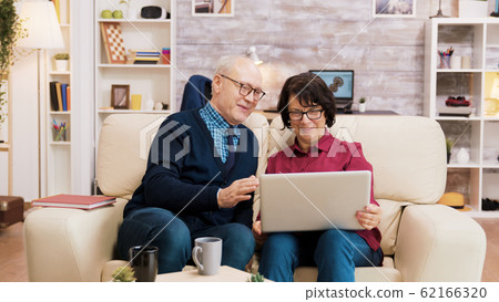 Seniors couple during a video call sitting on the couch 62166320