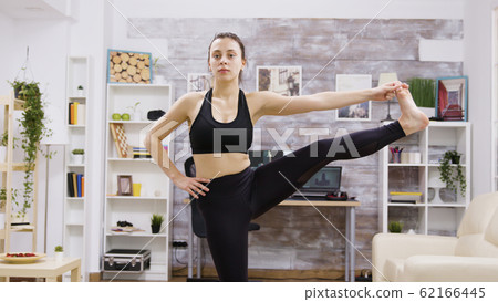 Young woman standing in one foot on mat 62166445