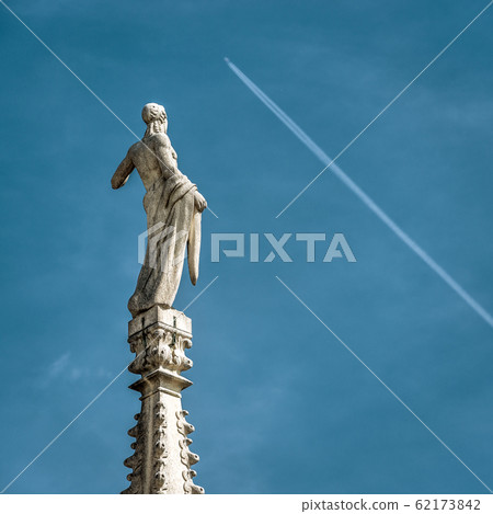 Statue on spire of Milan Cathedral closeup on blue Statue on spire of Milan Cathedral closeup on blue 62173842