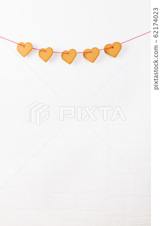 Heart shaped cookies hanging on a white wall. Simbol of cozy love and Valentines Day backrgound and festive concept Heart shaped cookies hanging on a white wall. Simbol of cozy love and Valentines Day backrgound and festive concept 62174023