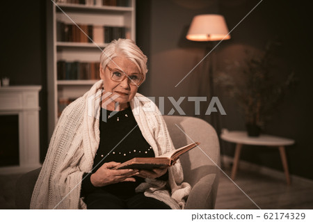 Elderly Woman Reads Old Book Sitting In A Chair. Elderly Woman Reads Old Book Sitting In A Chair. 62174329