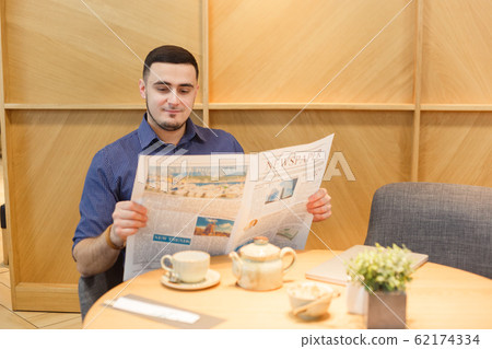 Young man in morning reading the newspaper. Sitting ia cafe 62174334