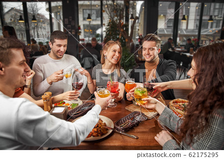 Happy multiracial young friends relax together talking laughing sit at cafe table, cheerful diverse students girls and guys people group studying having fun indoor, multicultural friendship concept 62175295