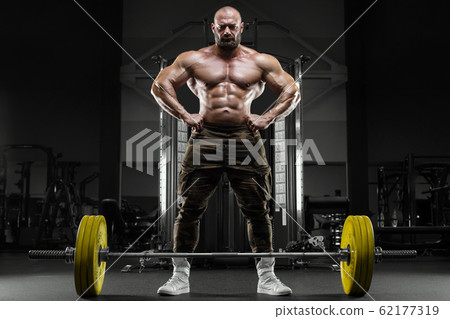 Bodybuilder strong athletic man pumping up muscles 62177319