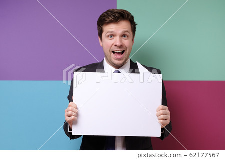 Young caucasian businessman in business outfit holding at blank canvas 62177567