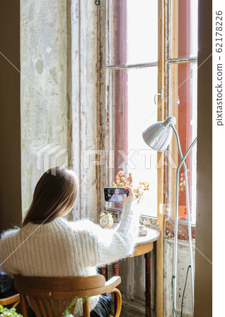 Girl behind uses technology and takes a selfie in a room with vintage furniture 62178226