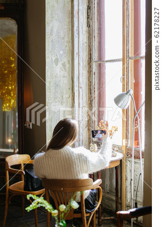 Girl behind uses technology and takes a selfie in a room with vintage furniture Girl behind uses technology and takes a selfie in a room with vintage furniture 62178227