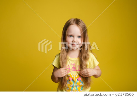 Adorable caucasian kid with long hair smiling at 62178500