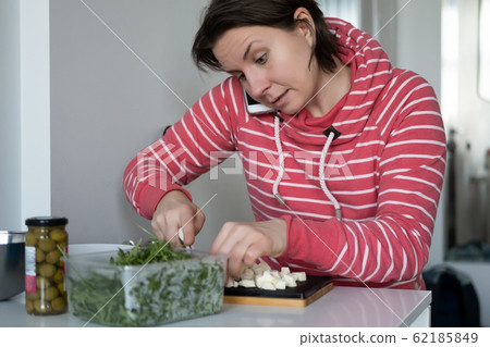 Young caucasian woman making salad cutting mozzarella Young caucasian woman making salad cutting mozzarella 62185849