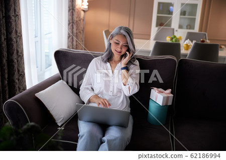 Cheerful woman answering the phone call stock photo Cheerful woman answering the phone call stock photo 62186994