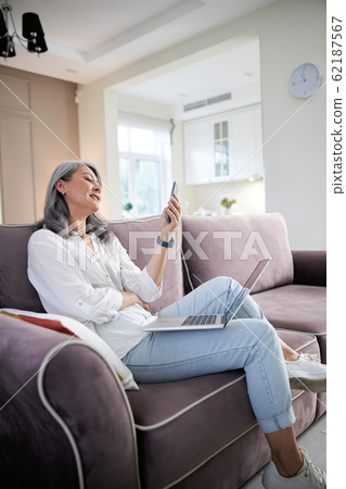 Smiling adult lady sending messages to friends stock photo 62187567
