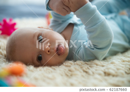 Funny baby showing tongue and looking away stock photo Funny baby showing tongue and looking away stock photo 62187660