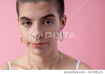 Serious girl with earrings and nose piercing stock photo Serious girl with earrings and nose piercing stock photo 62188124