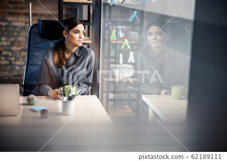 Cute brunette woman sitting at her workplace Cute brunette woman sitting at her workplace 62189111