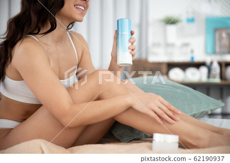 Smiling young woman holding bottle of lotion 62190937