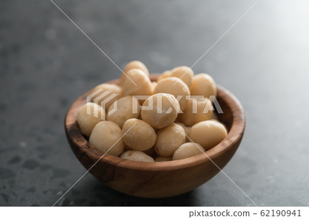 Macadamia nuts in olive wood bowl on terrazzo surface 62190941
