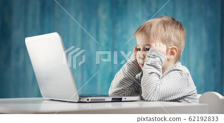 happy five years old child sitting with a laptop at table happy five years old child sitting with a laptop at table 62192833