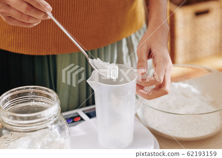 Woman putting spoon of lye in jar 62193159