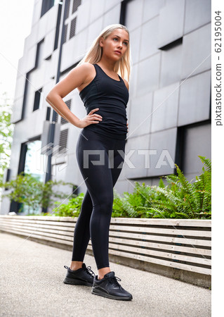 Confident Attractive Athletic Woman Standing Against Building In City Confident Attractive Athletic Woman Standing Against Building In City 62195004