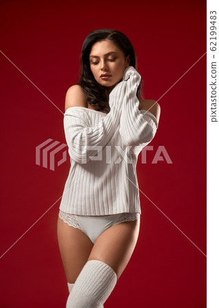 Sensual model posing in sweater and underwear. Sensual model posing in sweater and underwear. 62199483