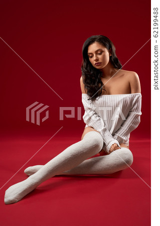 Brunette model posing on floor in sweater. Brunette model posing on floor in sweater. 62199488