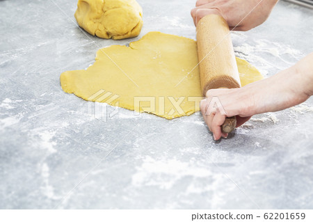 Women's hands roll out the dough. Preparation of dough, cookies, bread. Women's hands roll out the dough. Preparation of dough, cookies, bread. 62201659