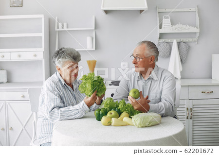Beautiful old couple prepare food in a kitchen Beautiful old couple prepare food in a kitchen 62201672