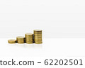 Growing stacked of coins on white table and 62202501