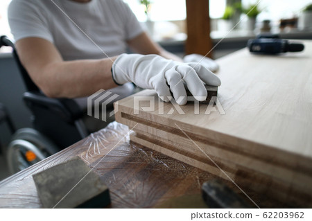 Man sits in a wheelchair and works as carpenter Man sits in a wheelchair and works as carpenter 62203962