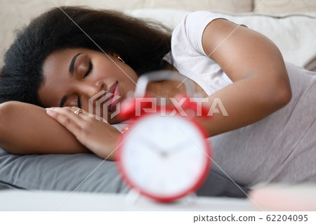 Woman is sleeping soundly, setting an alarm while. 62204095