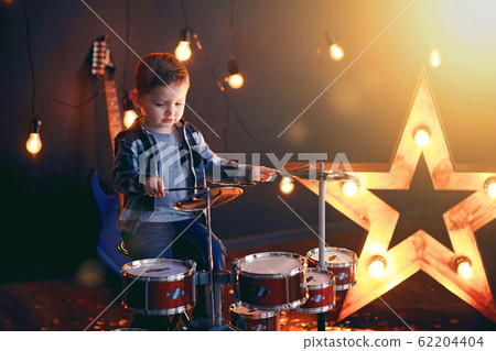 dark portrait of Beautiful boy playing the drums on a black background with smoke 62204404