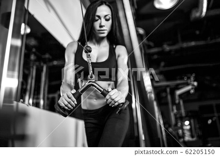 woman flexing muscles on cable machine in gym. exercise on triceps 62205150