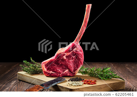 Raw juicy cowboy steak on wooden cutting board Raw juicy cowboy steak on wooden cutting board 62205461