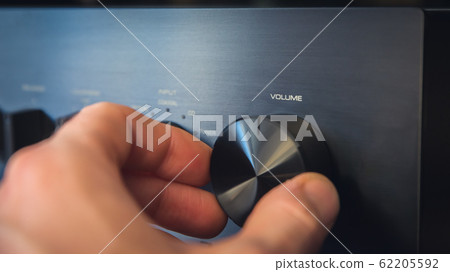 Hand turning a knob with output volume text 62205592